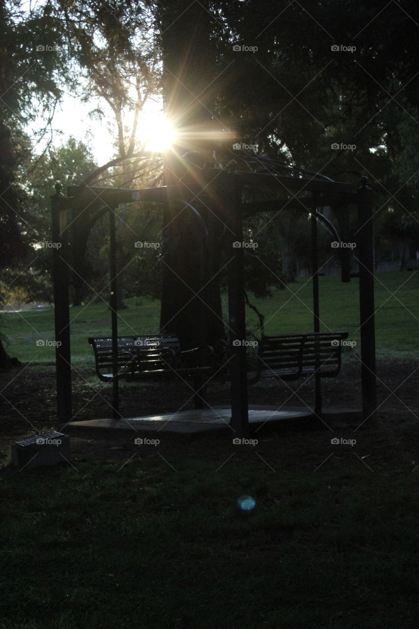 a silhouette picture of a double seat swing gazebo. Sunrise, Park, swing, gazebo, early morning