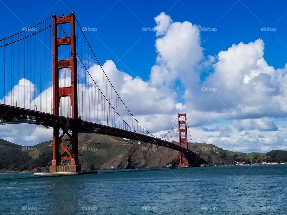 Golden Gate Bridge San Francisco, beautiful day with fluffy clouds and a blue sky to highlight the vibrant beauty of the bridge and water of the bay