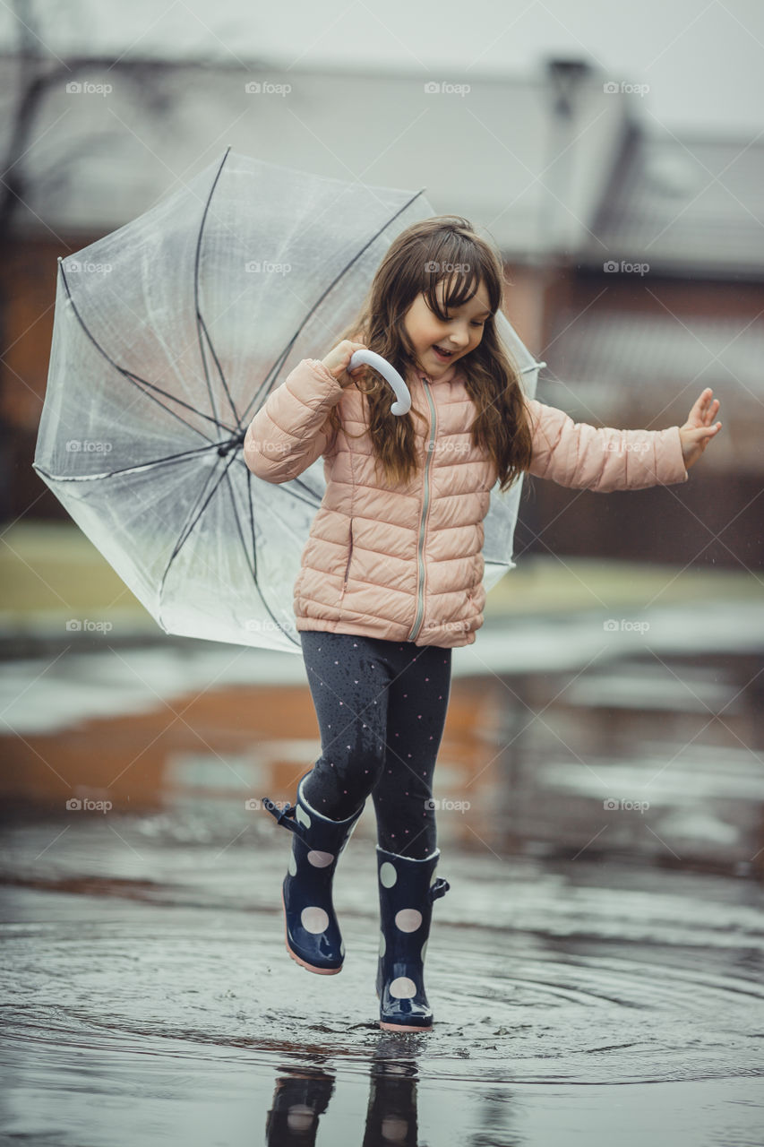 Little girl have fun under the rain.