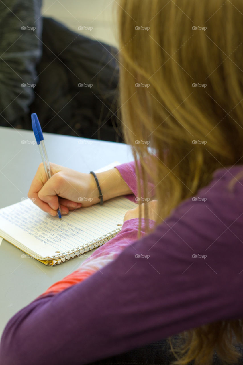 A female student taking notes in a classroom