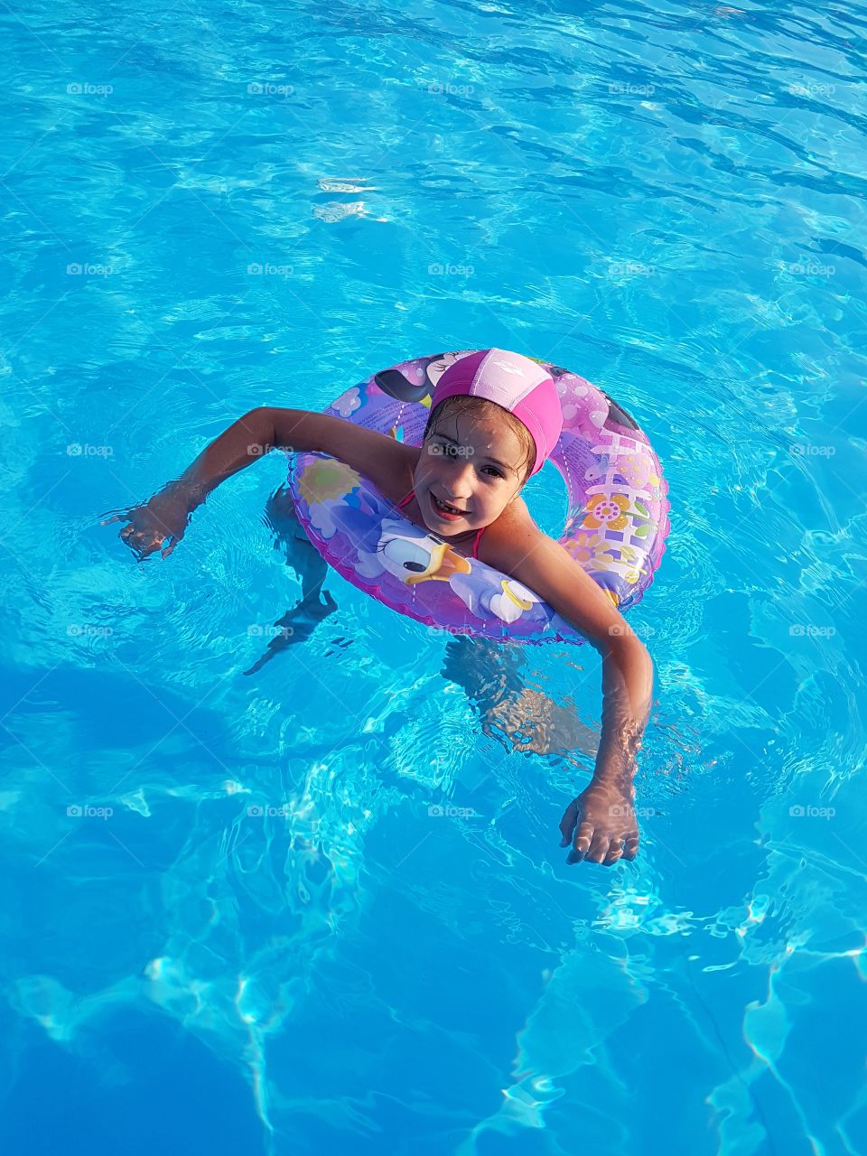 Little girl in pool with lifebelt in summertime