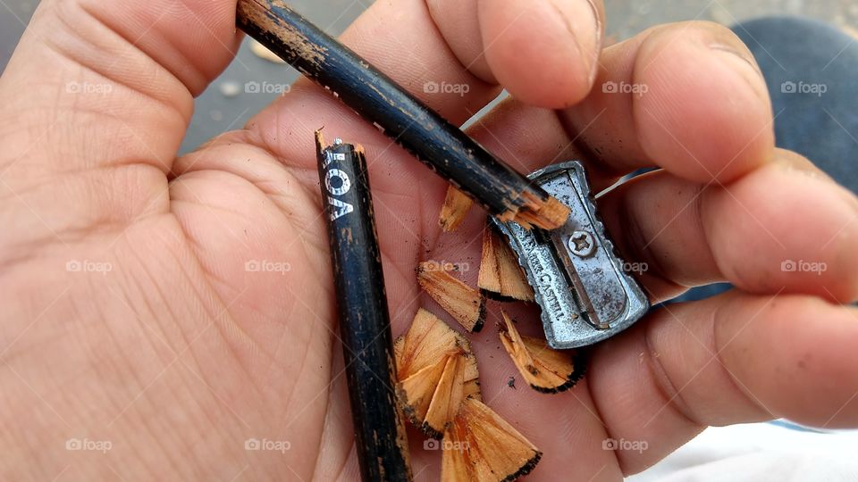 Mão com lápis quebrado e apontador.