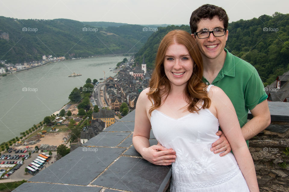 Couple standing near terrace wall against lake and mountain