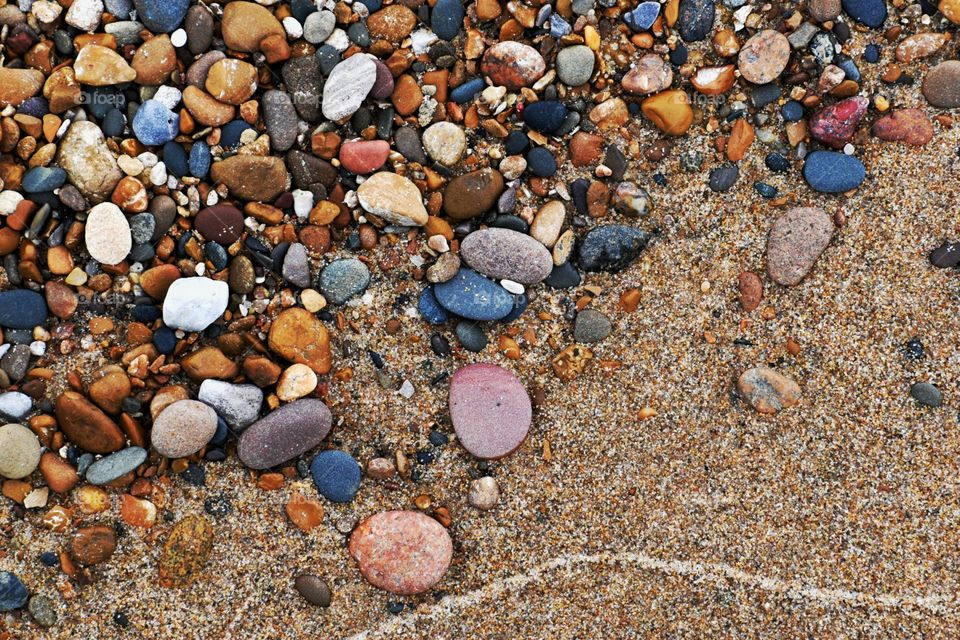 A vast array of sand and stone are pictured on the shores of Lake Huron. Plenty of natural and warm colors.
