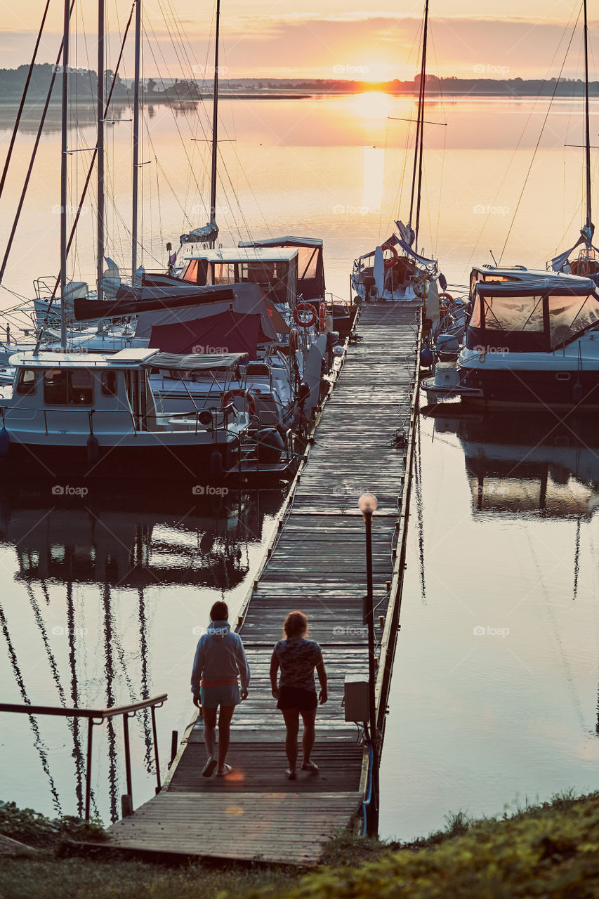 Yachts and boats moored in a harbour at sunrise. Candid people, real moments, authentic situations