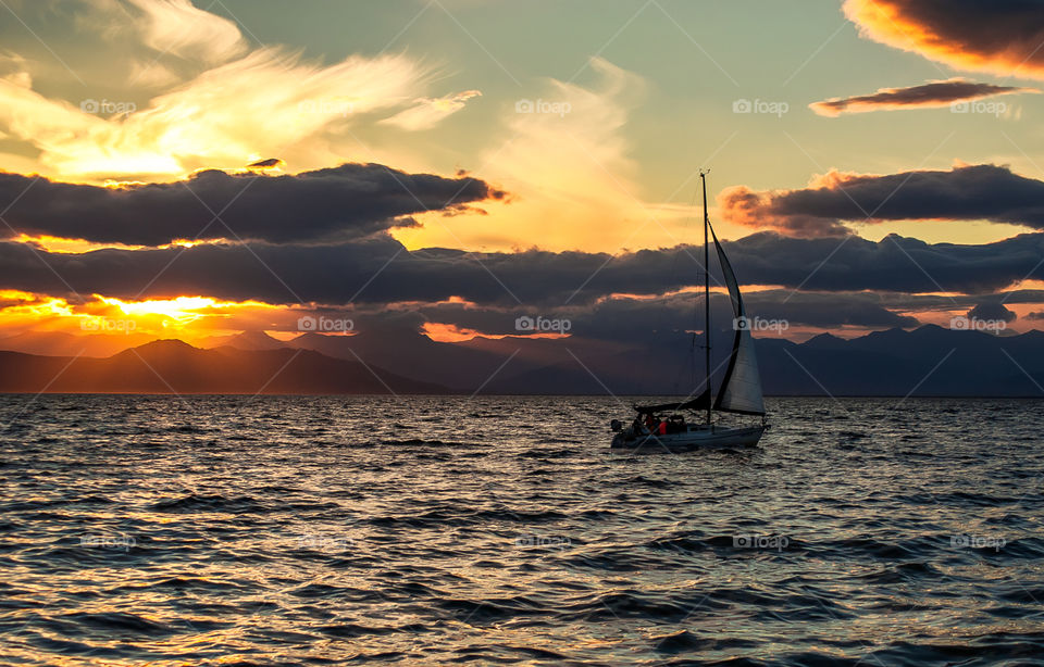 Kamchatka. white sail yacht sailing in the pacific ocean sunset time on the background