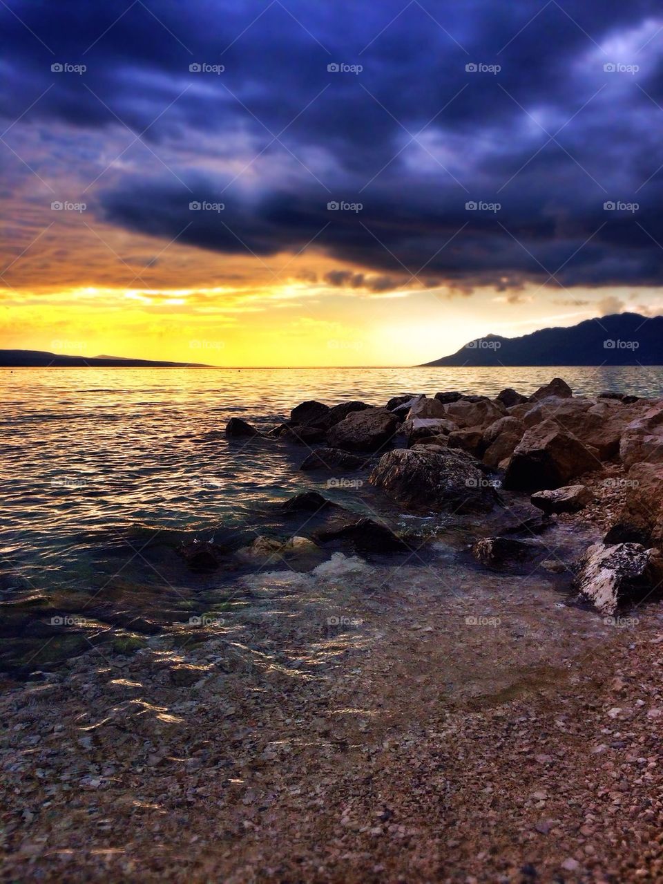 View of sea against storm cloud at sunset