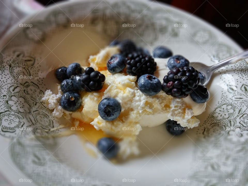 Cottage cheese with blueberries and dewberries, served with honey and sour cream