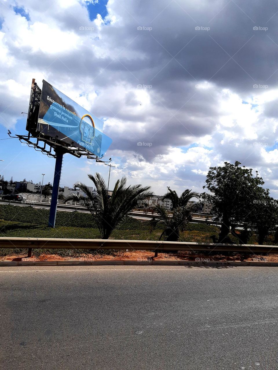 A tranquil scene outside Casablanca on January 1, 2025, featuring a main road lined with simple houses, surrounded by green fields. The soft breeze and quiet atmosphere create a peaceful rural escape.