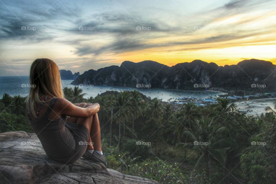 Girl sitting on rock looking sunset