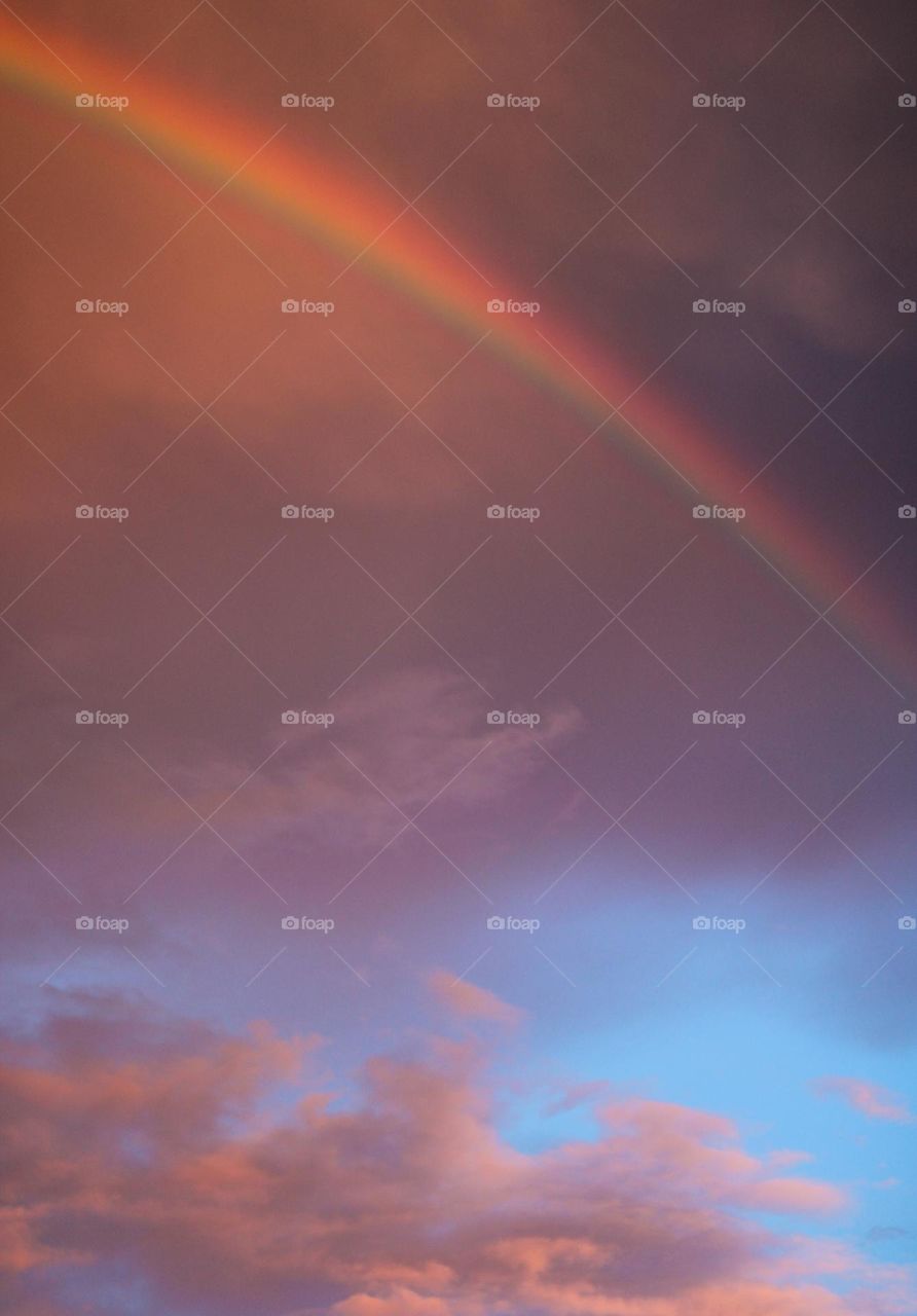 Low angle view of rainbow against sky during sunset.