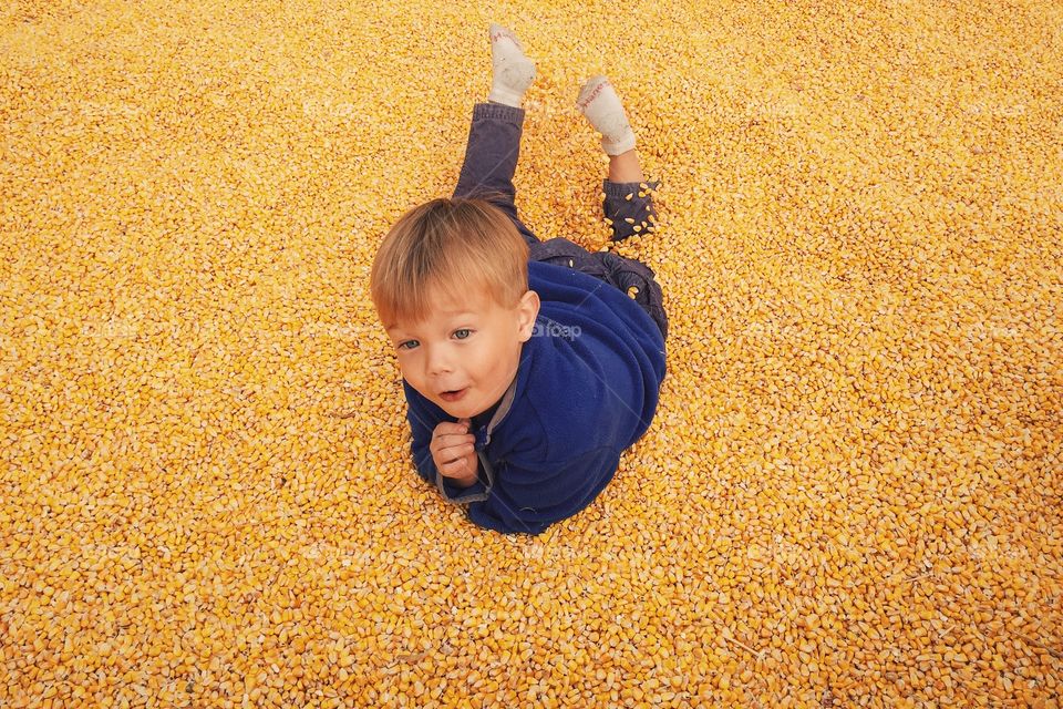 Child playing in corn pit