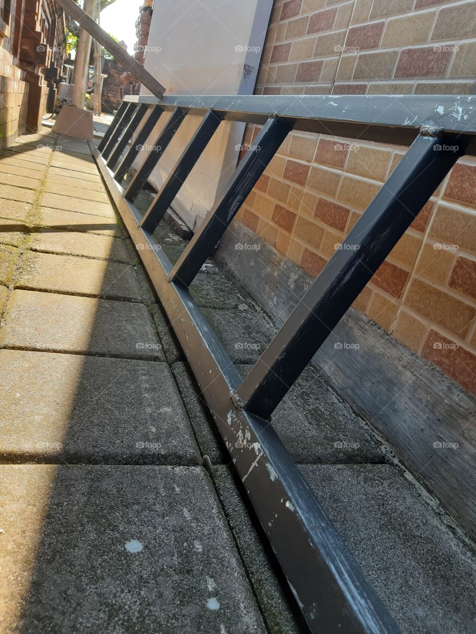 The steel ladder is lying horizontally on the wall