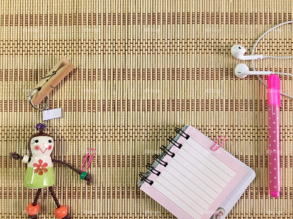 Note color pencil hanging dolls and earphone on the mat background 
