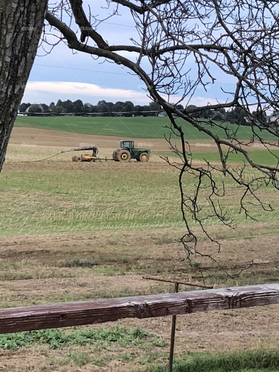 Tractor and farmer fertilizing farm crop 