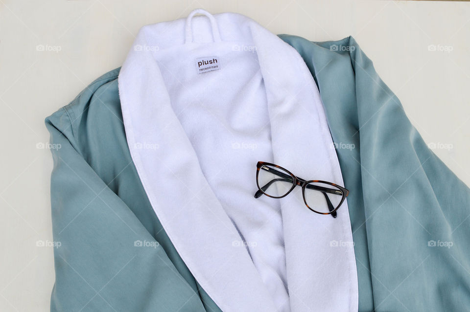 Blue bathrobe laid out with a pair of glasses