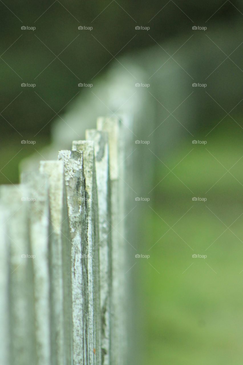 An old wooden white painted picket fence bordering a winding road through a Japanese Chinese cemetery. 