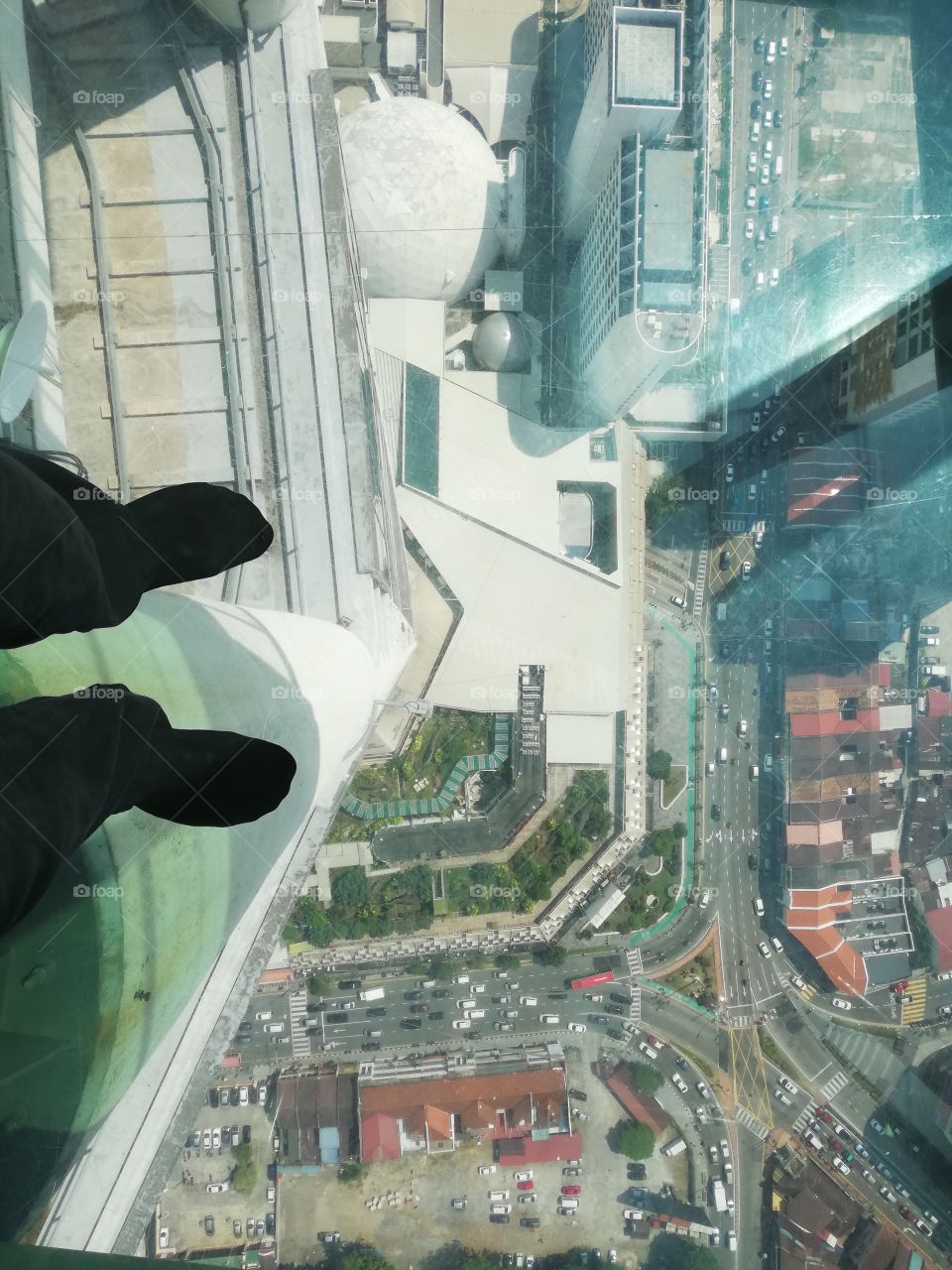 Feet on glass walkway on skyscraper