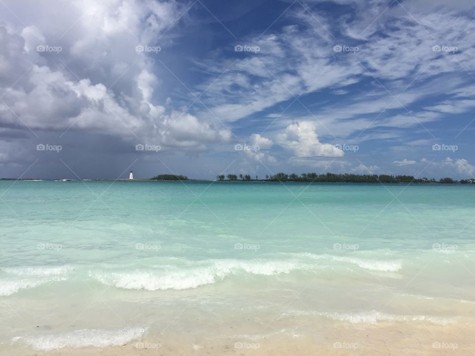 Crystal clear beach with small island and light house in Nassau Bahamas 