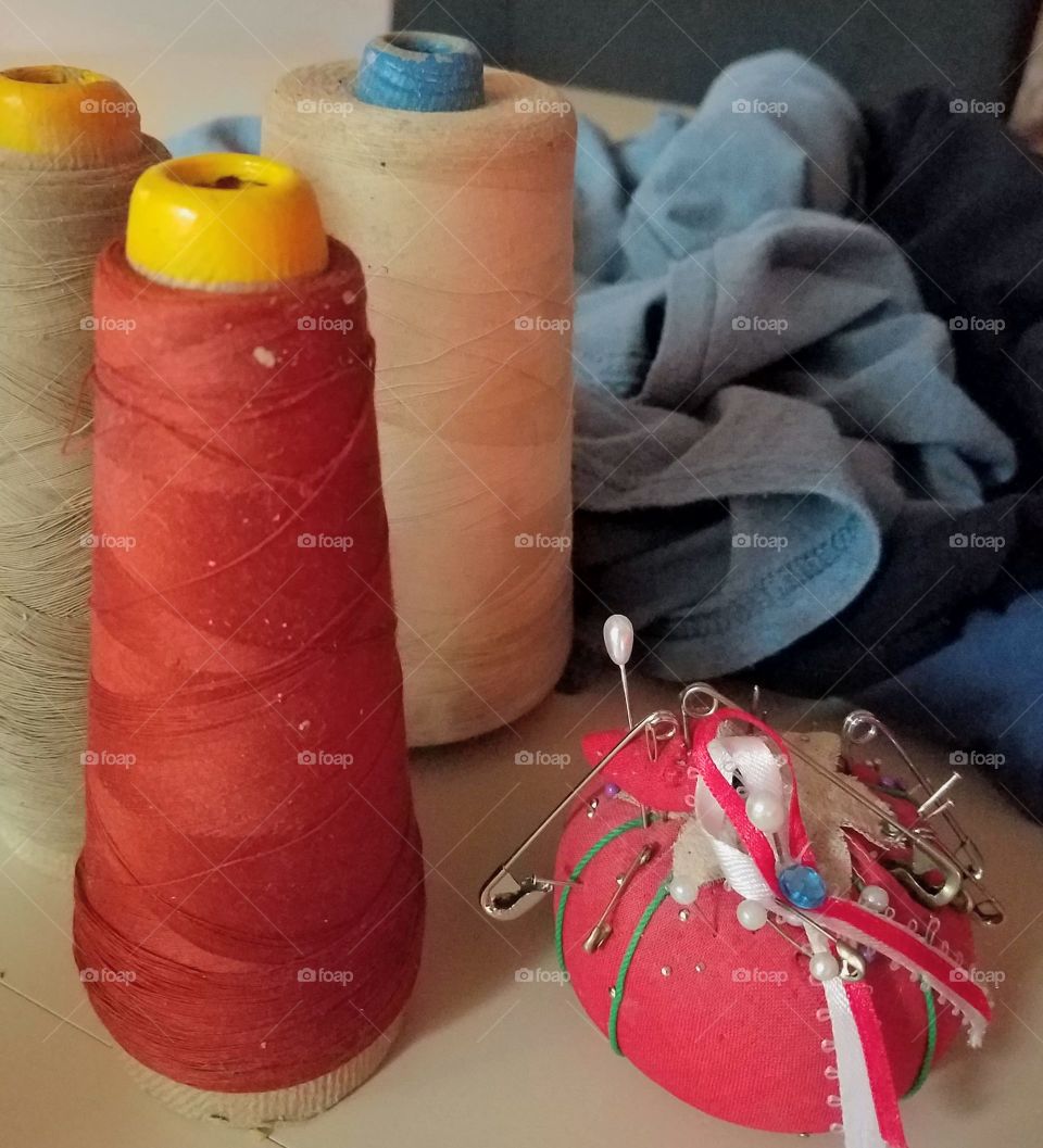 Spools of threads different colors, pin cushion with safety pins, hat pins, common pins & sewing needles. Shirt to mend by hand.