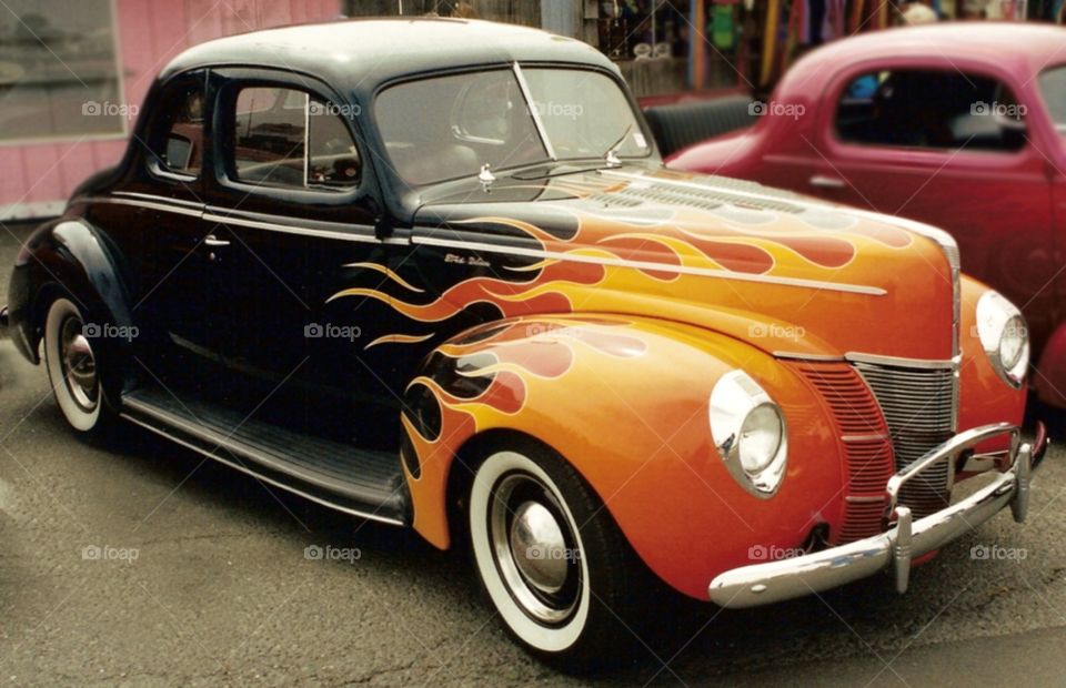 Old car with bright orange flames on the front end.