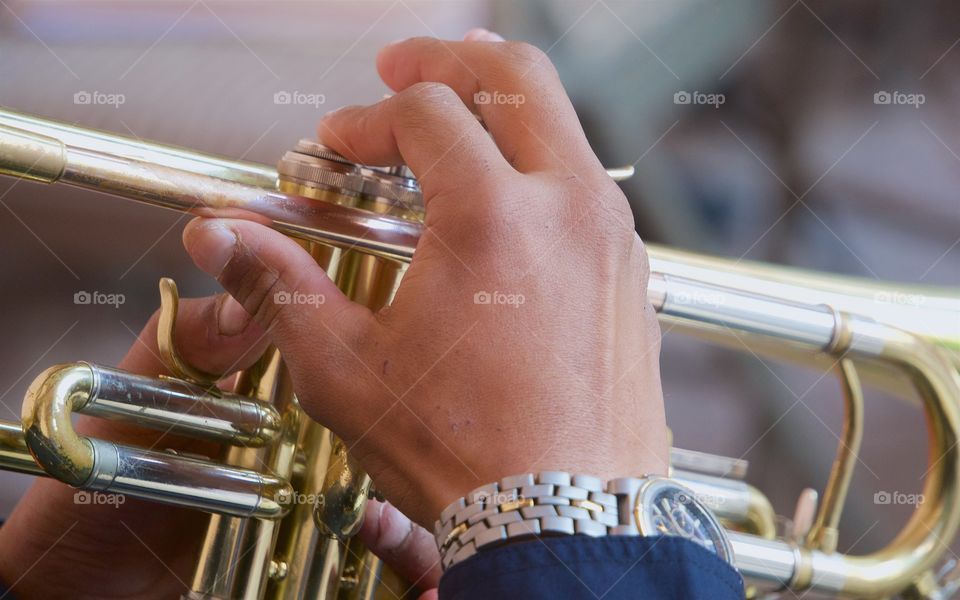 A closeup of a youth's hands playing the trumpet.