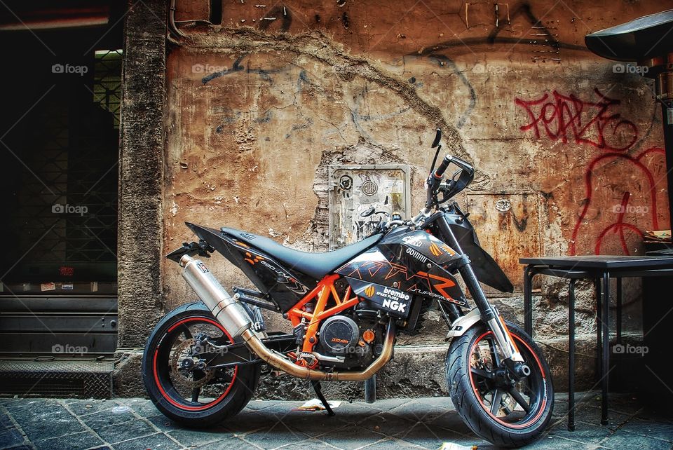 Supermoto . A flashy motorcycle parked against crumblingRoman wall