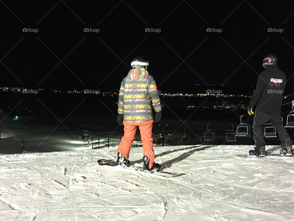 Rear view of snowboarders at night