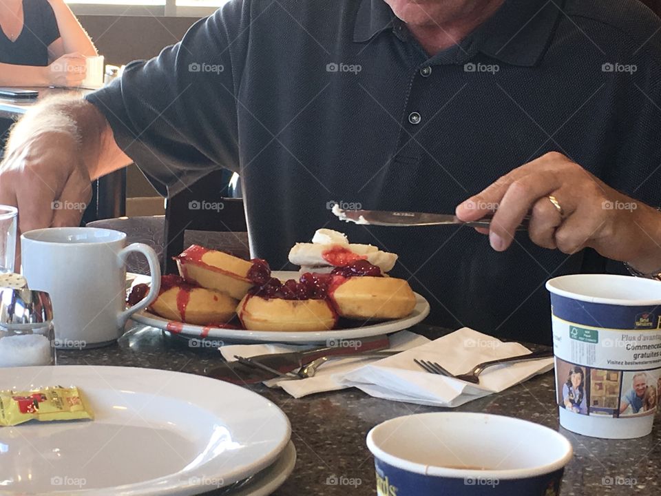 A big breakfast of round waffles drizzled with raspberry sauce and drenched with whipped cream 