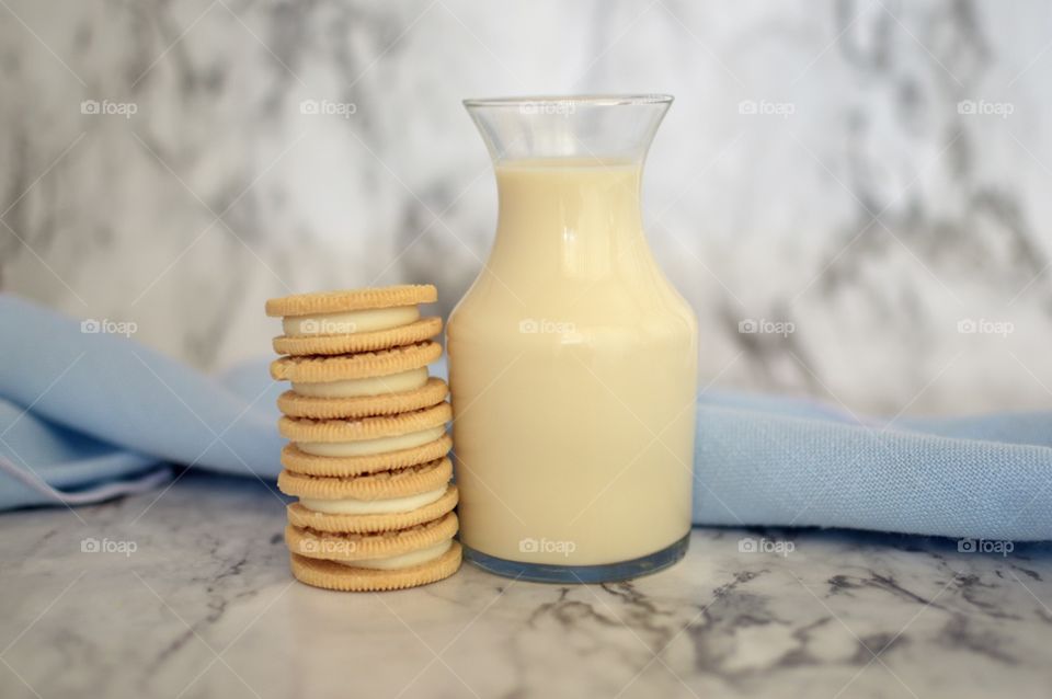 Oreo double stuff cookies stack next to a carafe of milk on a marble backdrop