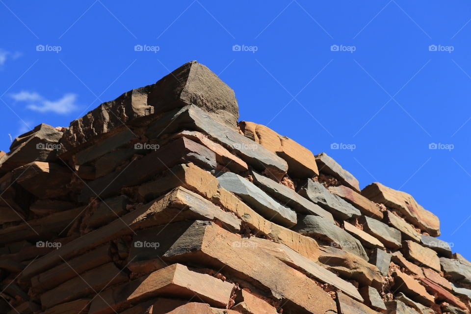 Stacked stone wall against a vivid blue sky, the homestead remains of some of the first Australian settlers 