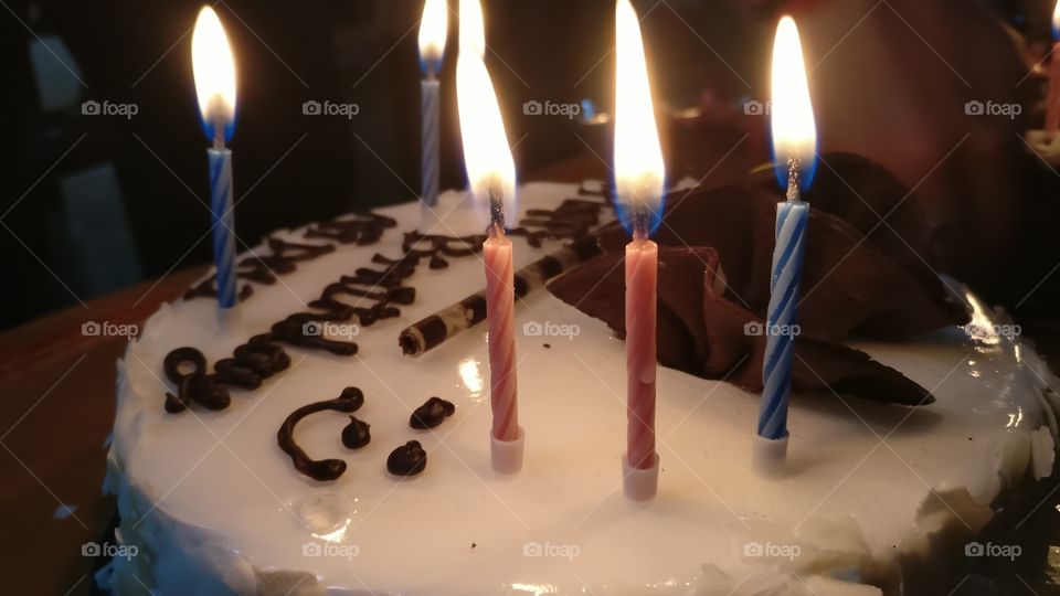 Closeup macro shot of birthday cake with three candles lit with bright flame. pinapple chocolate cake happy birthday