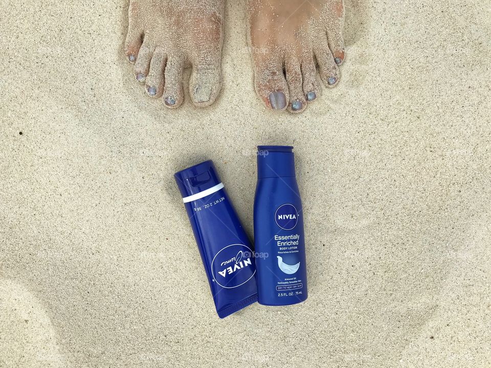 Nivea lotion on a sandy beach with feet
