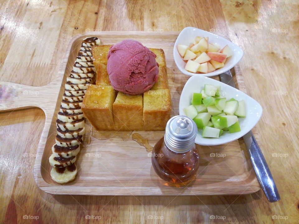 Sweet honey toast and fresh fruits in wooden plate.