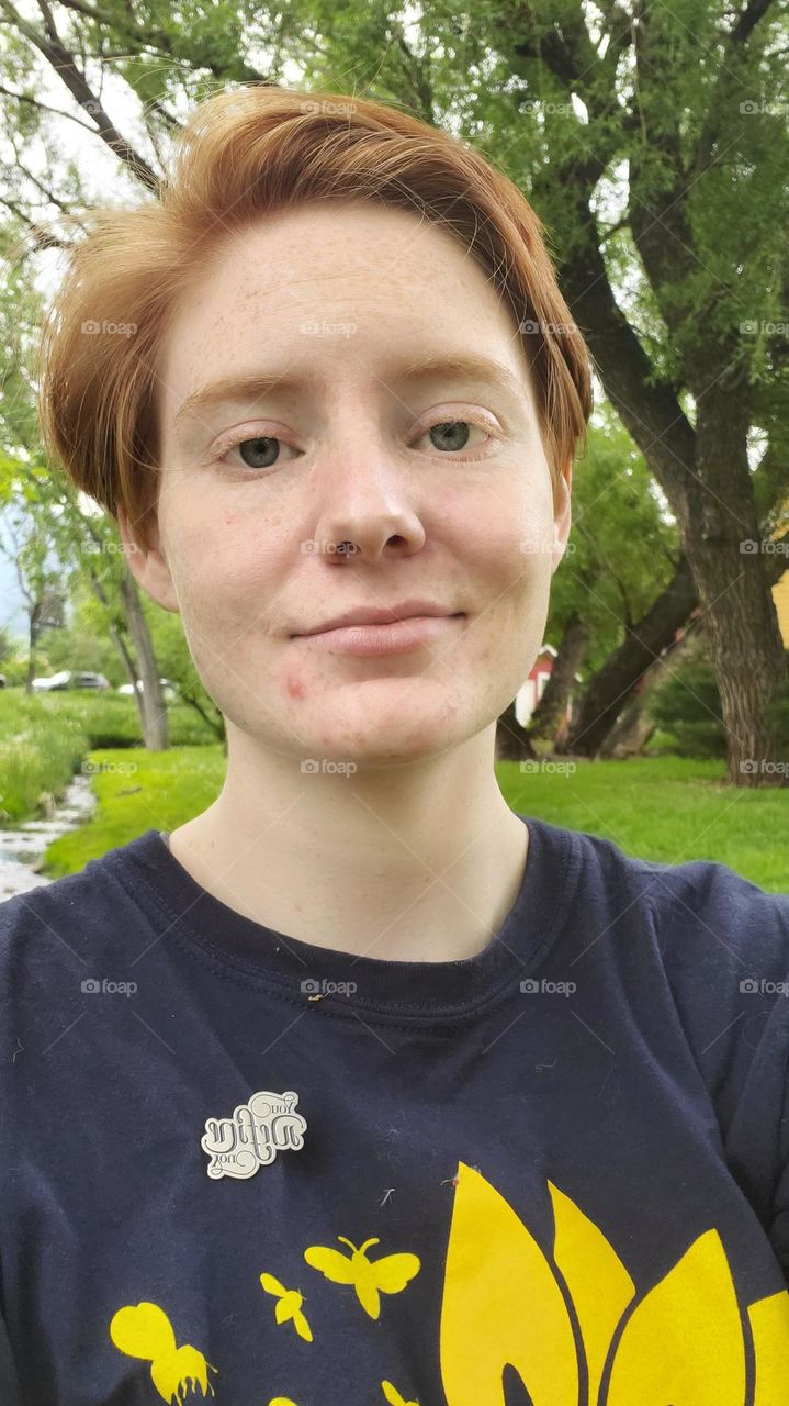 Self Portrait. Close up, red head in front of trees and stream