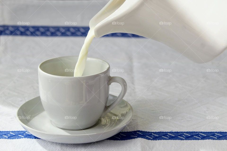 Pouring milk into white mug