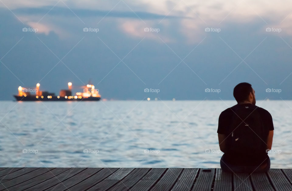 Young Man Sitting Alone At The Dock And Enjoying The Night View
