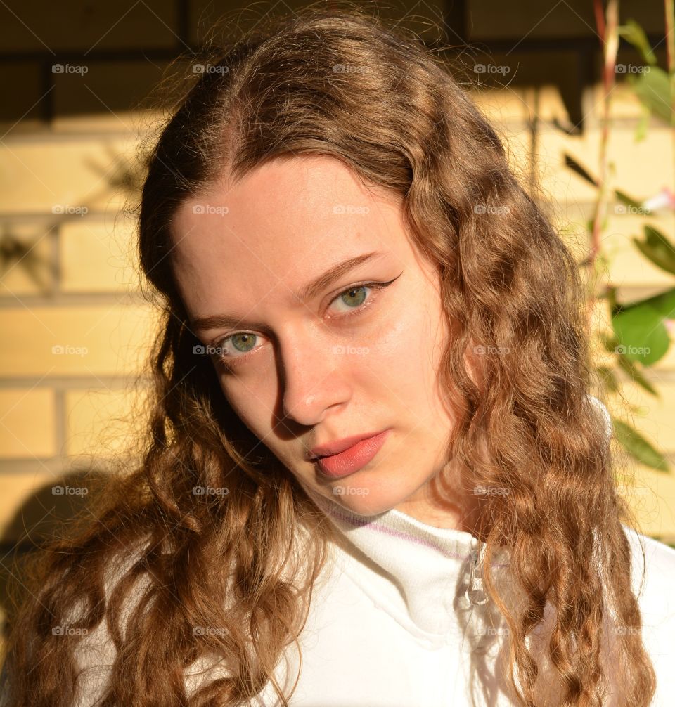 brunette girl beautiful portrait close up in sunlight brick wall background