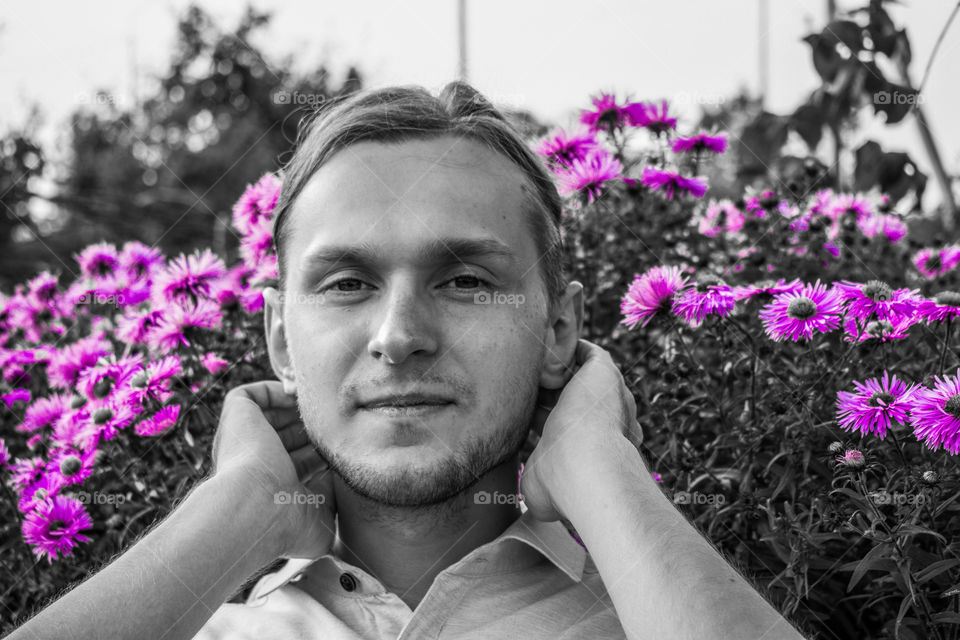 Black and white portrait of a young man with a colorful purple flower element.