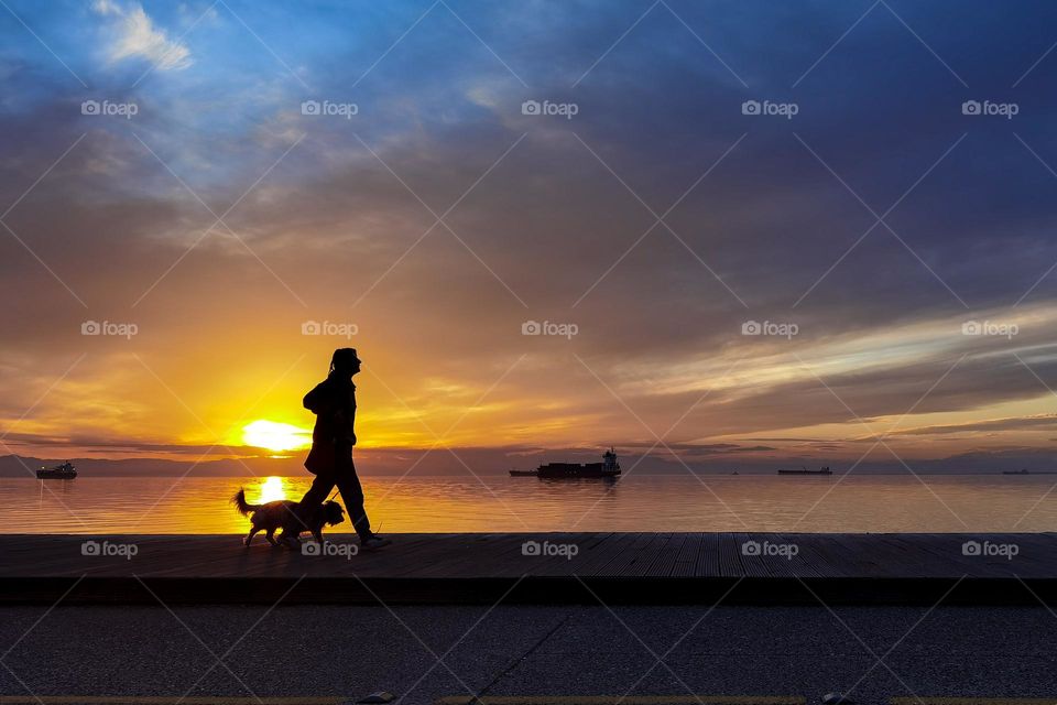 Man waking his dog met the sunset in Greece