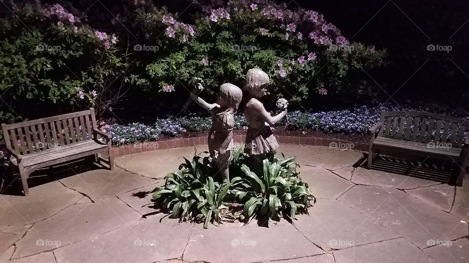 Children statue in garden at night