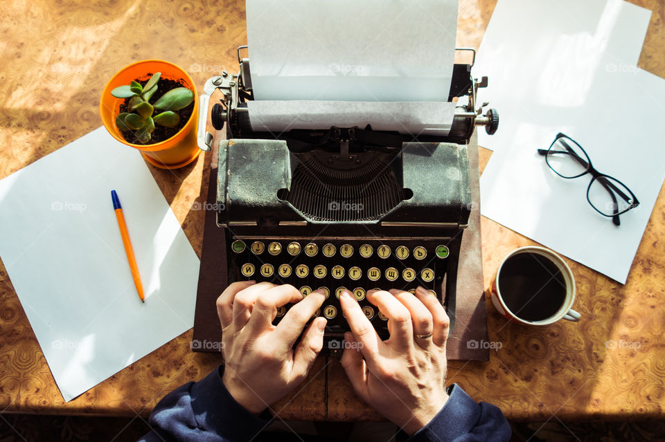 A young writer is writing a new book on an old typewriter.