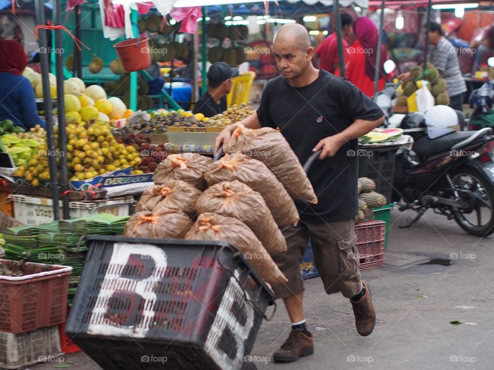 Hardworking man carry a bundle of wholesale groceries