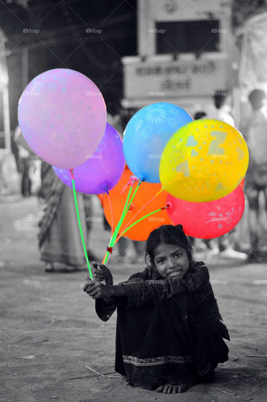 dark side of fun fair ...a girl selling balloons still happy what she have
