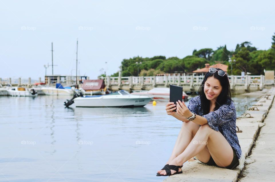 Portrait of young happy business woman relaxing, working in city, beach at Adriatic sea. Laptop. Technology. Selfie. Social media. Video call.
