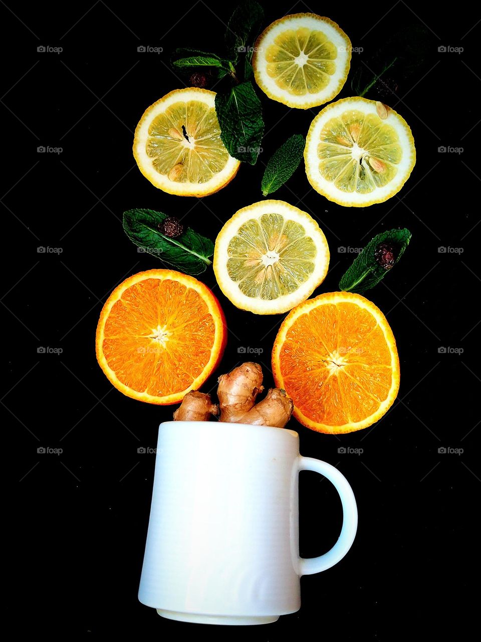 Fruit.  A white mug from which a tree grows: trunk - ginger root, flowers: mugs of orange orange and mugs of yellow lemon, leaves - green mint leaves.  Black background. Fruit tree