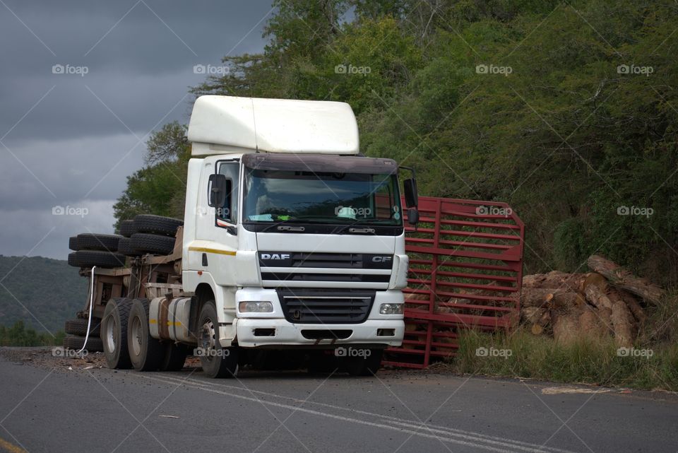 Road Accident: The Trailer Capsized Spilling A Load Of Timber Of Timber On The Side Of The Road
