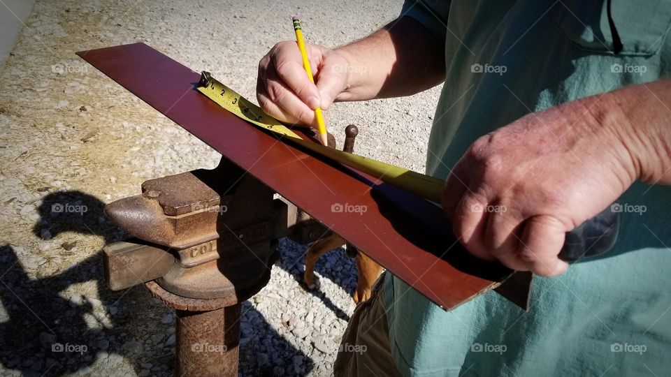 Man measuring steel to cut...blue collar jobs...hard working hands