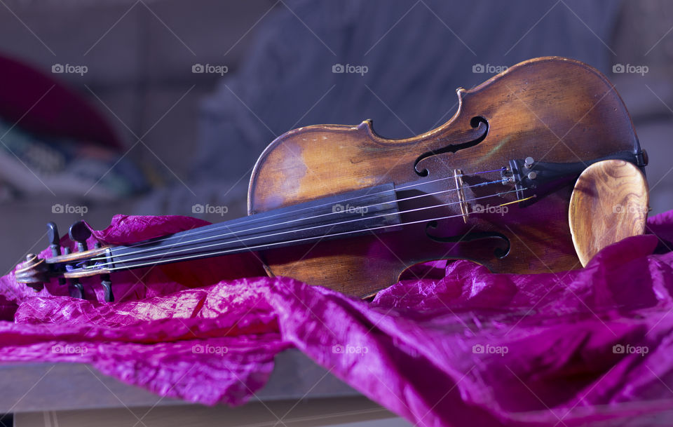 Violin on a purple bedspread.