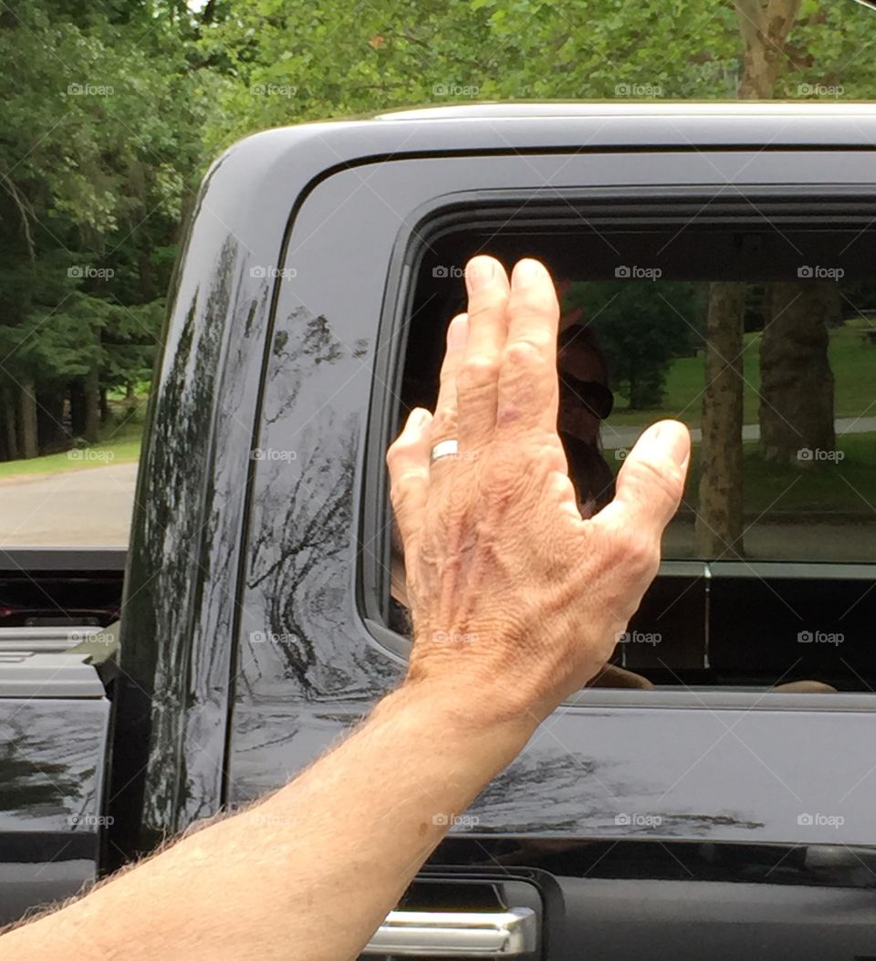 Man waving goodbye with his hand being the main focus of the photo.